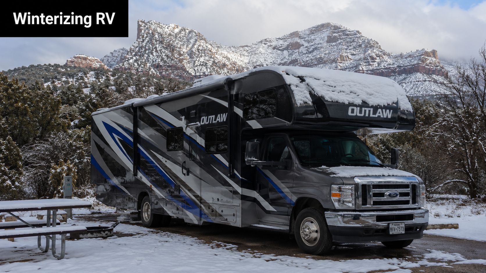 A modern Outlaw RV parked in a snowy campsite with snow-covered mountains in the background.